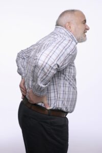 Bulging discs or herniated discs can cause back pain like this man is experiencing as he holds his lower back.